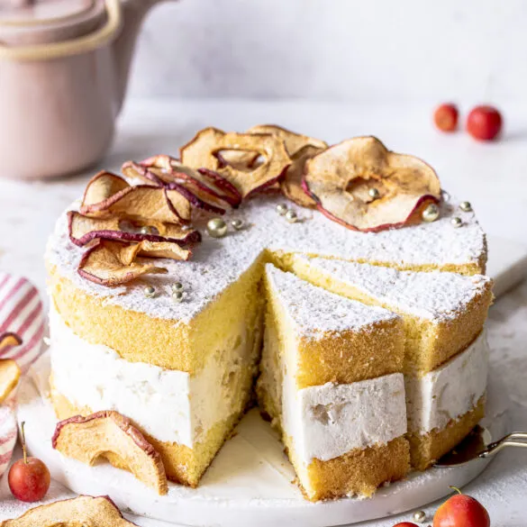 Bratapfel-Käse-Sahne-Torte aus der Vogelperspektive, mit Puderzucker bestäubt und mit Apfel-Chips verziert.