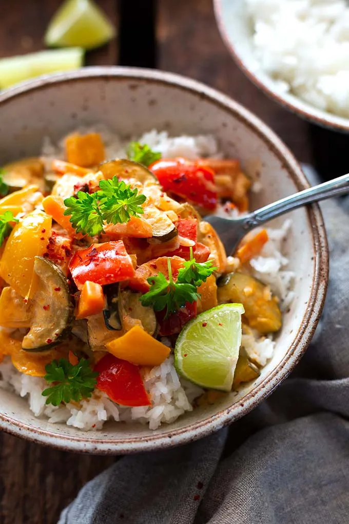 Buntes vegetarisches Curry mit Kokosmilch in einer Schale, angerichtet mit frischen Limetten.