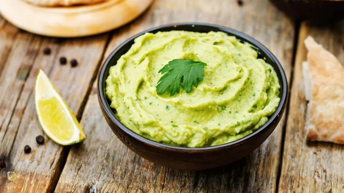 Cremige Guacamole in einer Schale, serviert mit Nachos als Beilage oder Snack für das Mittagessen
