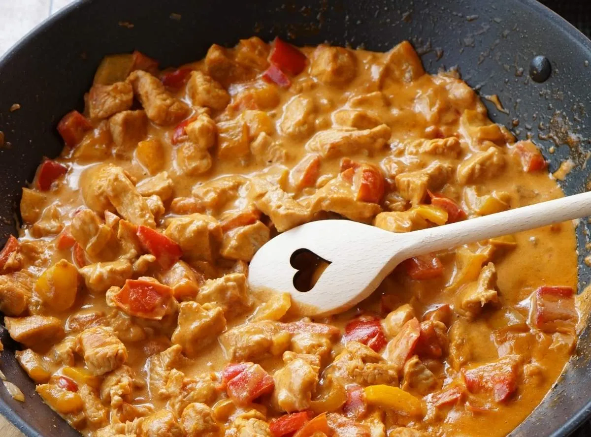 Cremiges Paprika-Sahne-Hähnchen in einer Pfanne, garniert mit frischen Kräutern