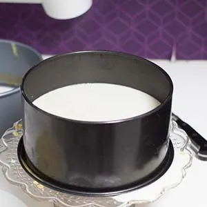 Das Gießen der cremigen Mandelschicht auf den vorbereiteten Biskuitboden