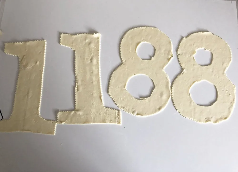 Das Zusammensetzen des Number Cake mit Tupfen der Frischkäsecreme