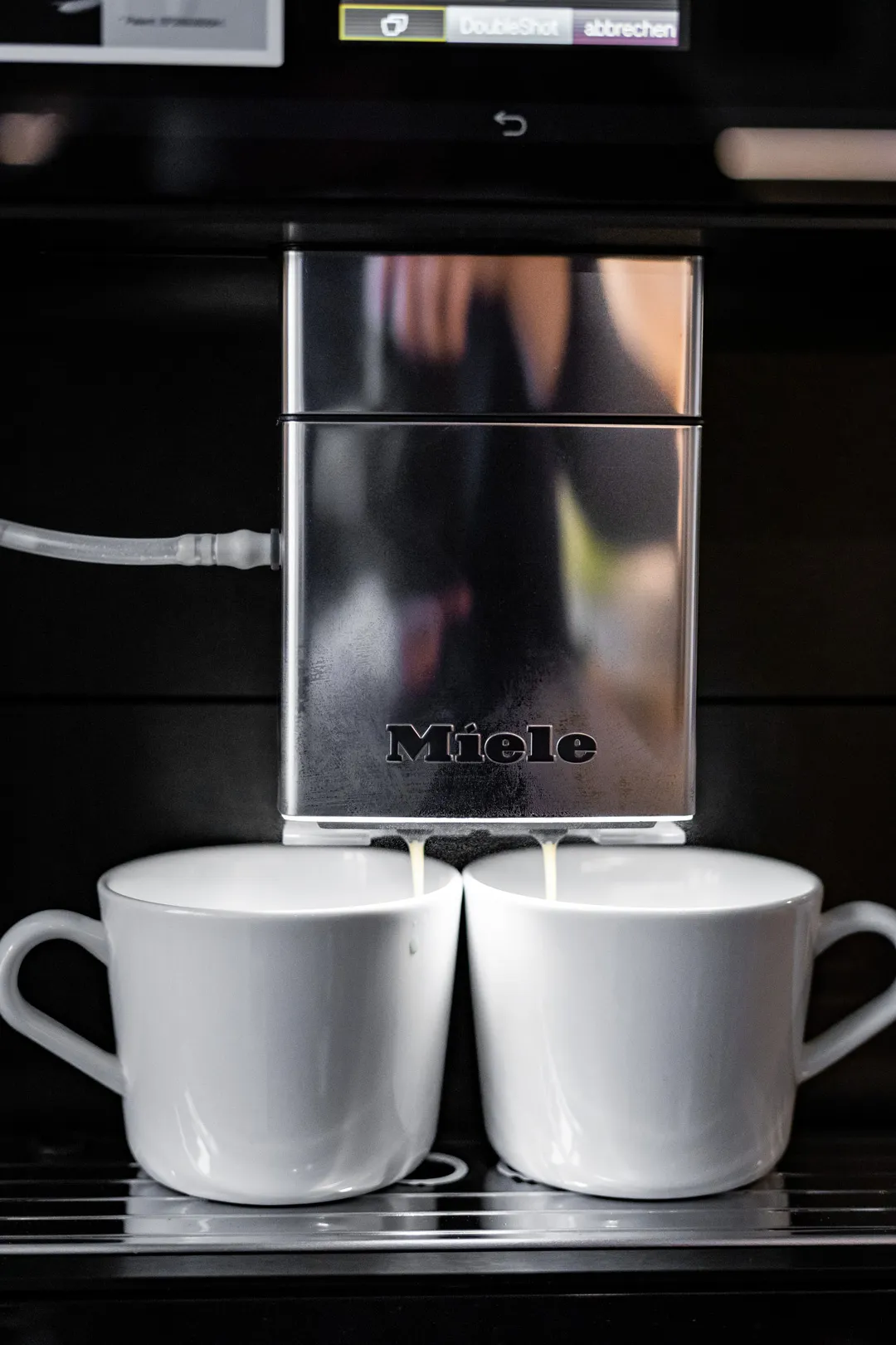 Der Miele CM 7750 Kaffeevollautomat bereitet eine Kaffeespezialität zu, sichtbar am Auslauf.