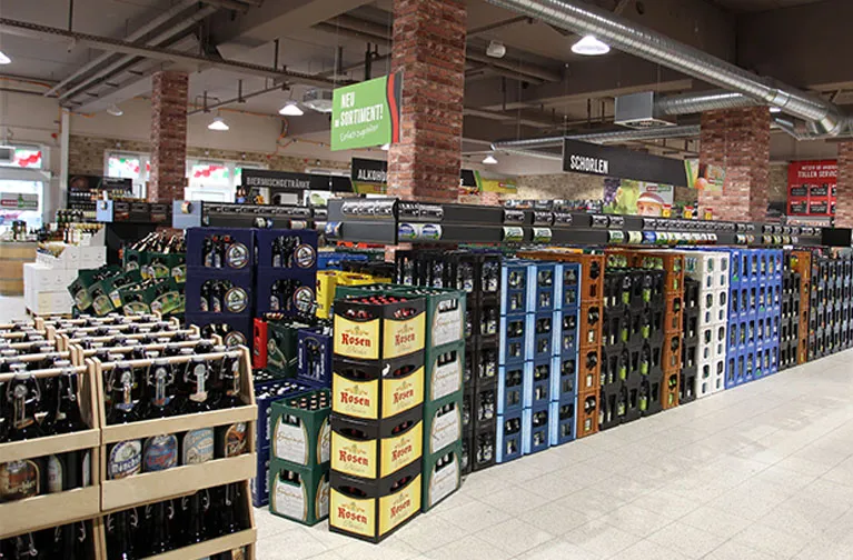 Detailansicht der Weinabteilung im Markgrafen Getränkemarkt Naumburg mit schräg gestellten Holzkisten und Flaschen