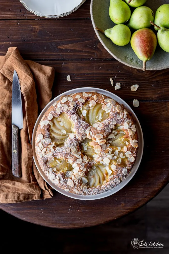 Detailaufnahme des Birnen-Mandel-Kuchens mit frischen Birnenscheiben und Mandelblättchen.