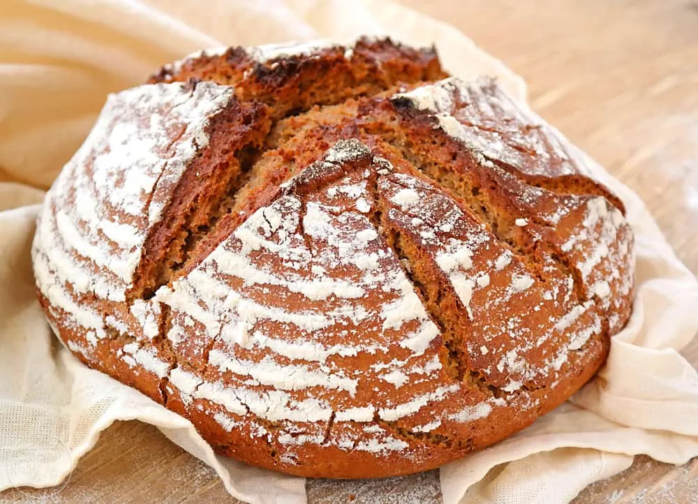 Detailaufnahme eines angeschnittenen rustikalen Bauernbrots mit Sauerteig, das eine dichte Krume zeigt