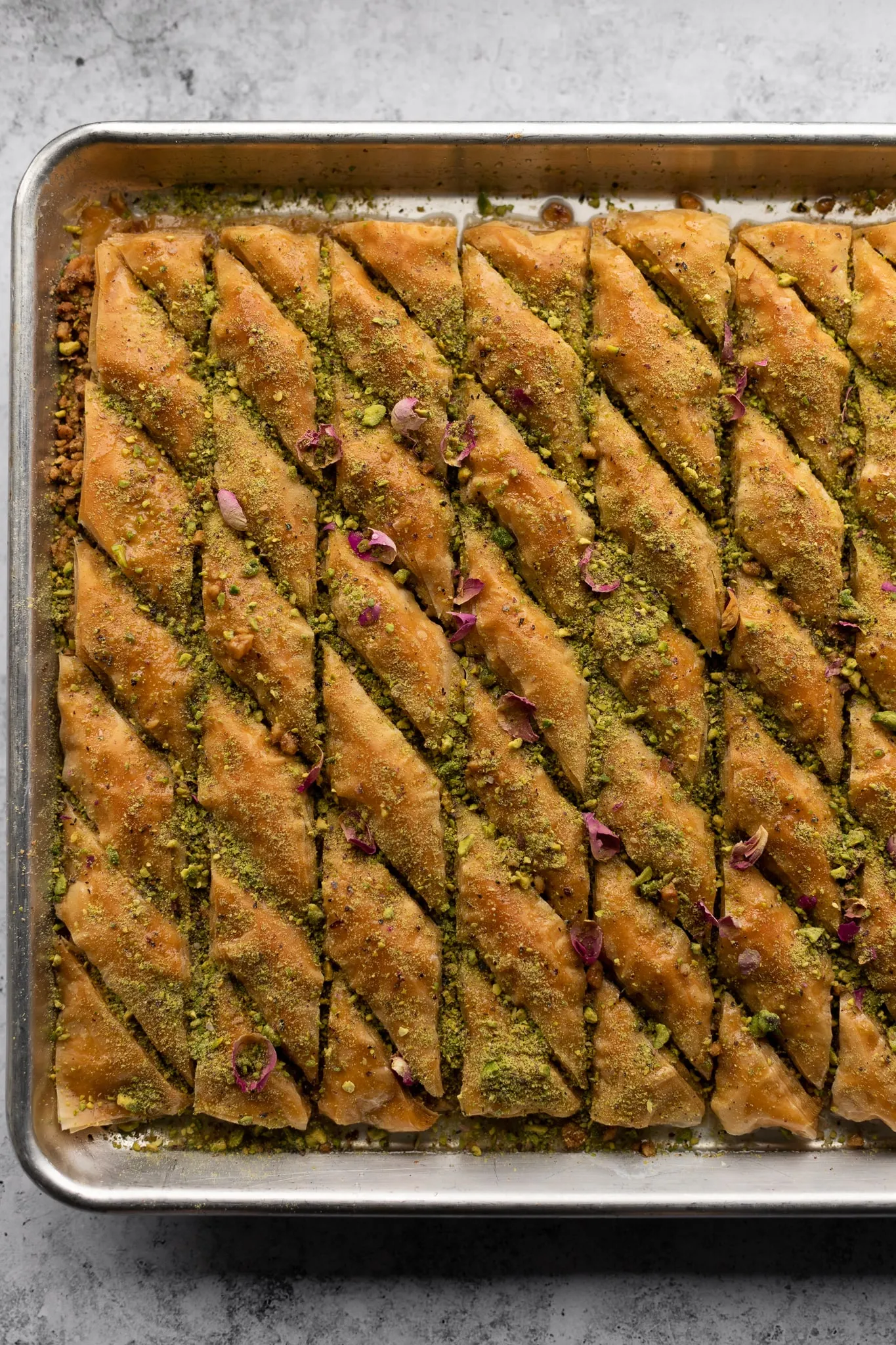 Dicker, goldener Zuckersirup wird langsam über frisch gebackenes Baklava gegossen