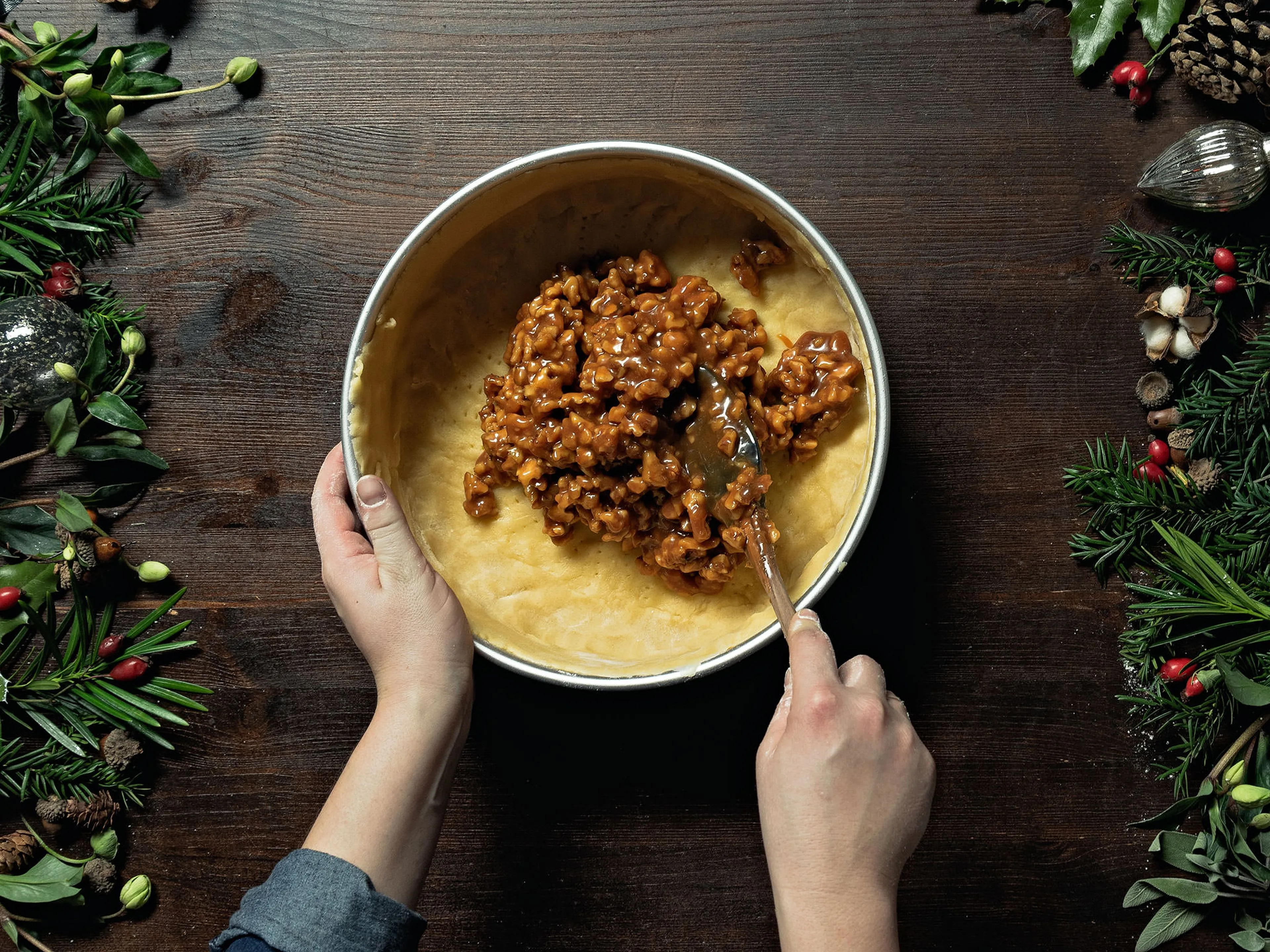 Die Bündner Nusstorte wird zusammengesetzt: die Nussfüllung wird in den Mürbeteigboden gegeben, mit einem Teigdeckel bedeckt und die Ränder mit einer Gabel versiegelt.