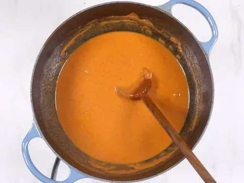 Die Butter Chicken Sauce köchelt in einem Topf, Spuren von Butter steigen an die Oberfläche.