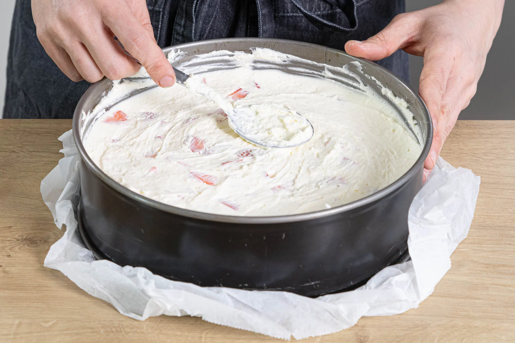 Die cremige Frischkäse-Erdbeer-Masse wird glatt auf den Tortenboden gestrichen