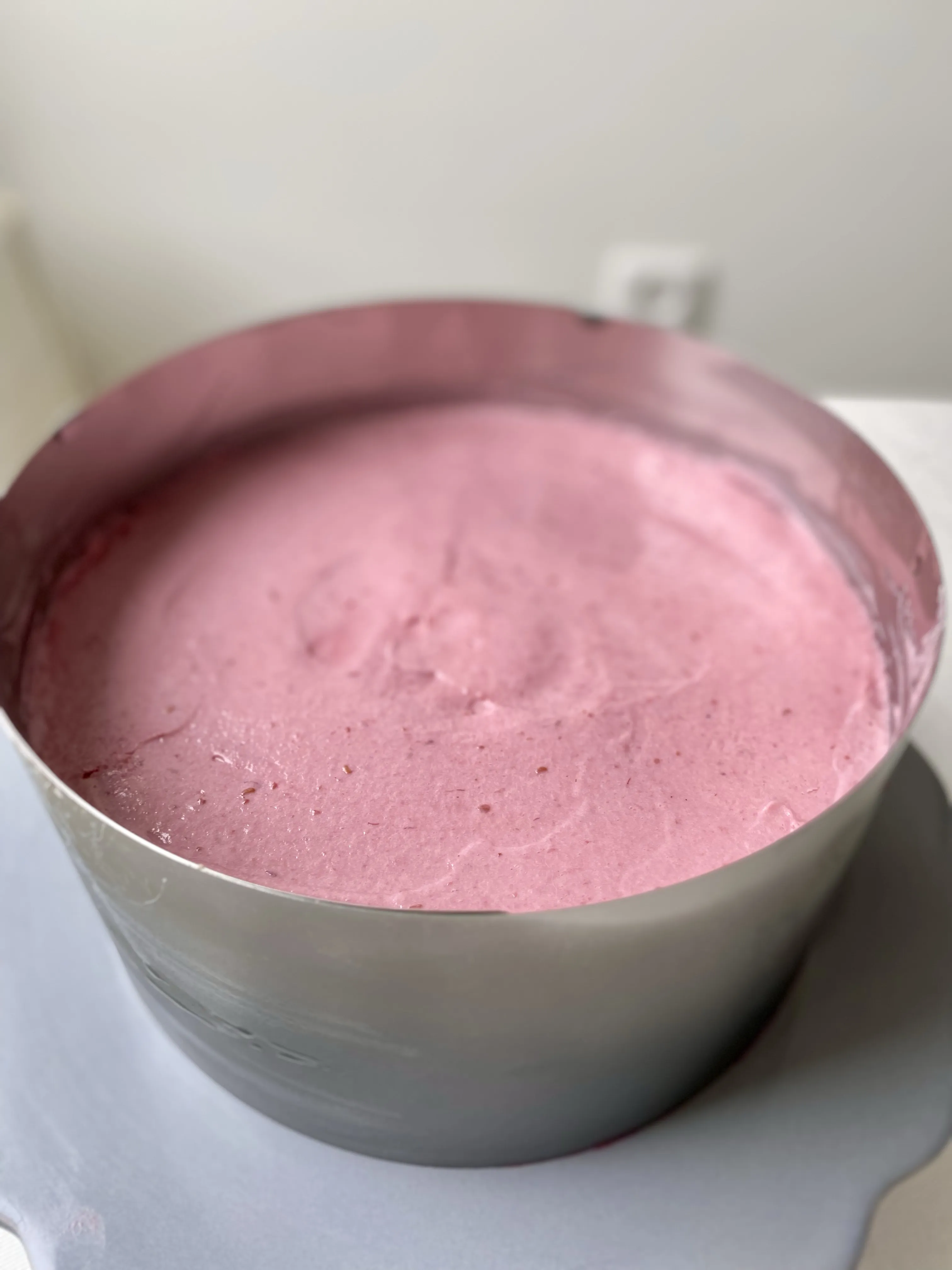 Die cremige Himbeer-Mousse wird auf den unteren Biskuitboden der veganen Torte aufgetragen.