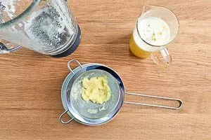 Die gemixte Ingwer-Zitronen-Flüssigkeit wird durch ein Sieb in eine Kanne abgeseiht