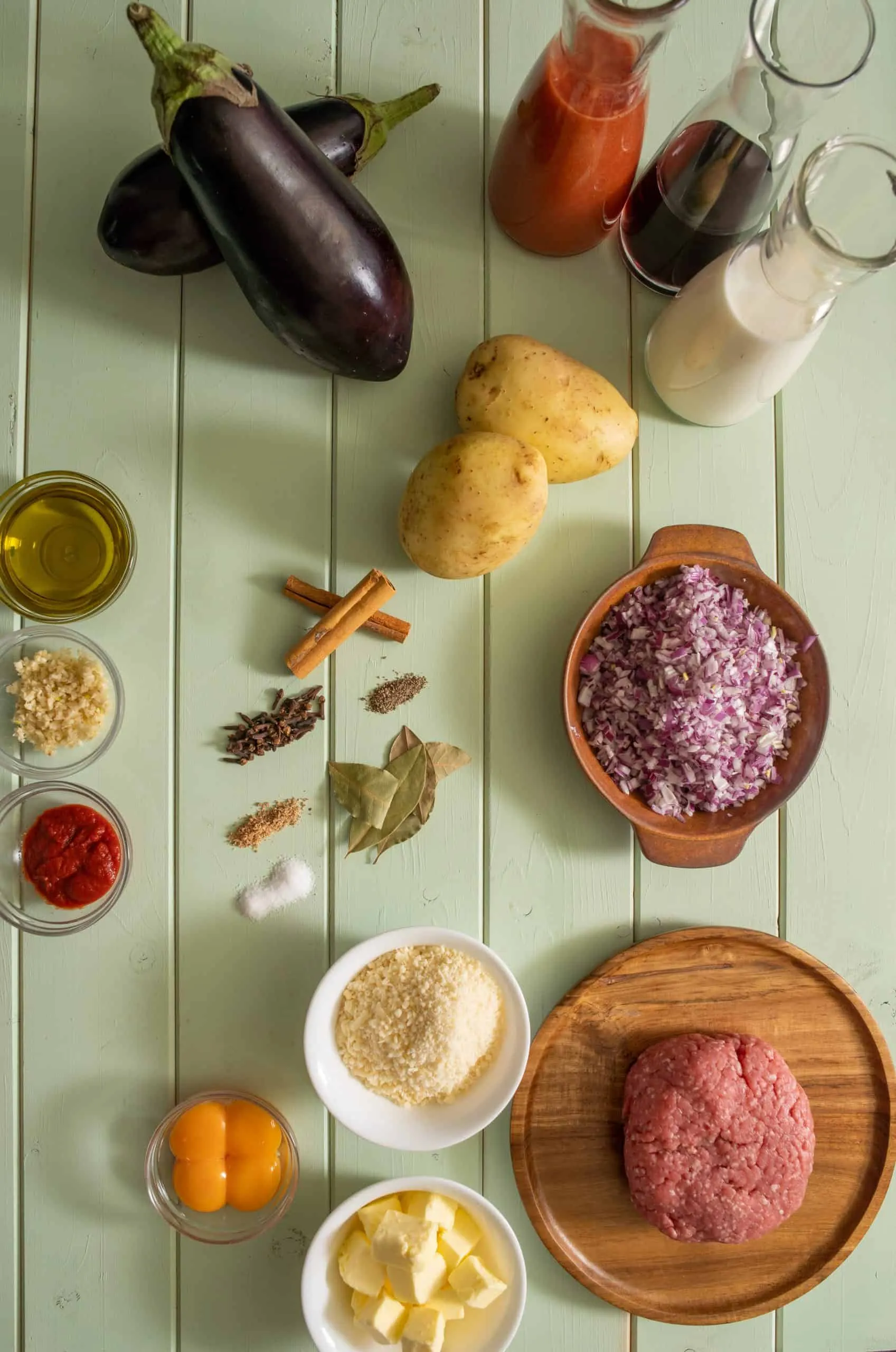 Die Hauptzutaten für unser Moussaka Rezept, darunter frische Auberginen, Kartoffeln und Fleisch