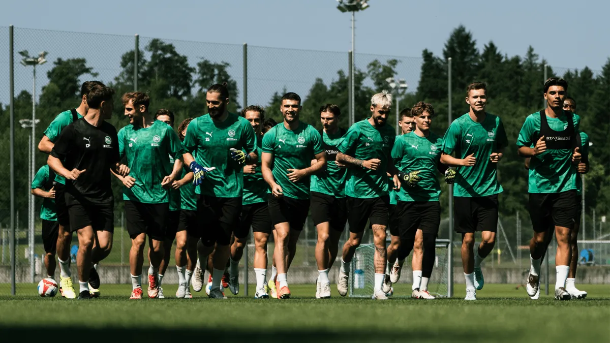 Die Mannschaft des FC St. Gallen beim konzentrierten Training auf dem Rasenplatz, umgeben von Mitarbeitern.