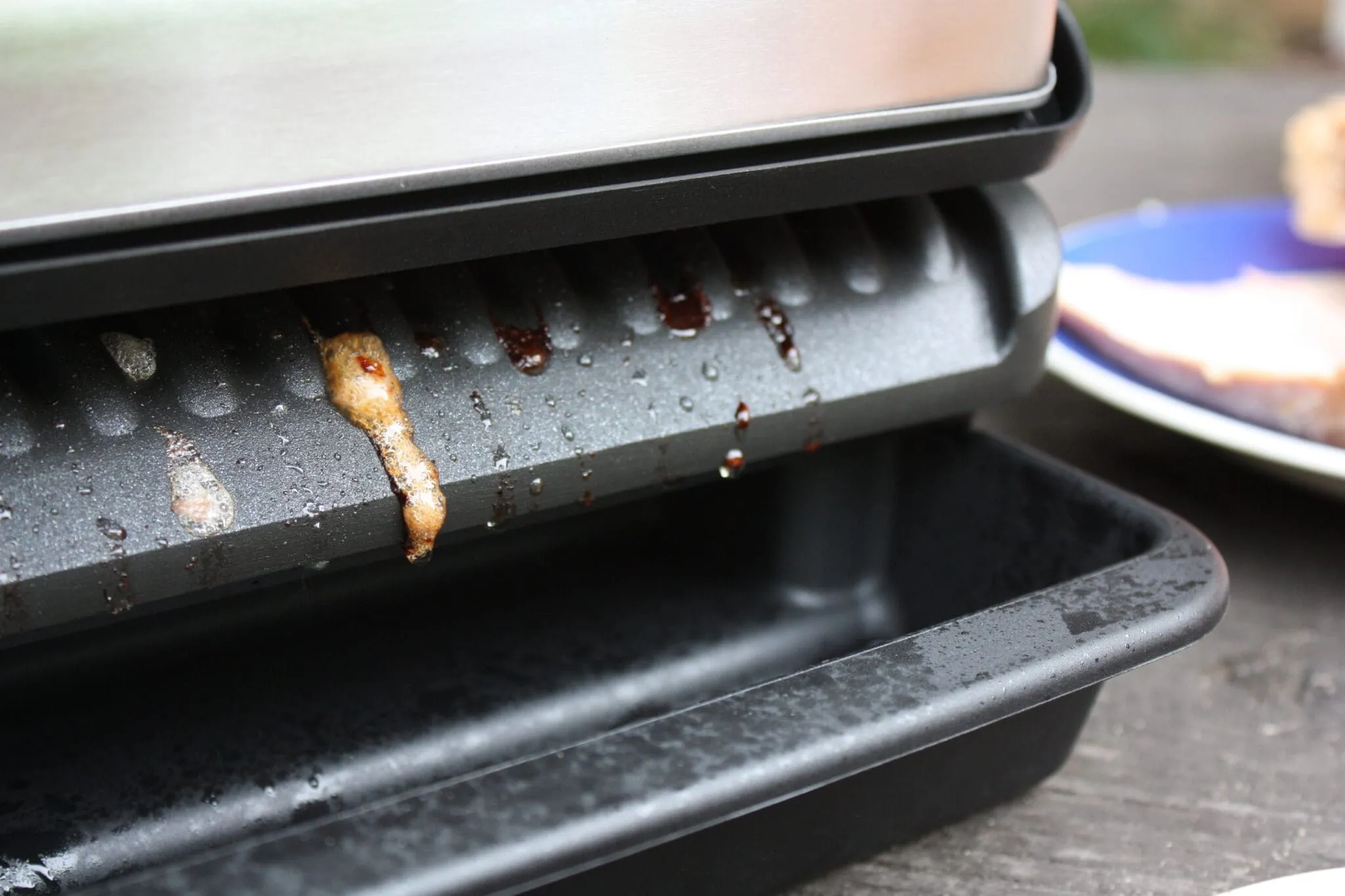 Die untere Grillplatte ist oft geneigt, um Fett und Flüssigkeit in die Auffangschale abfließen zu lassen.