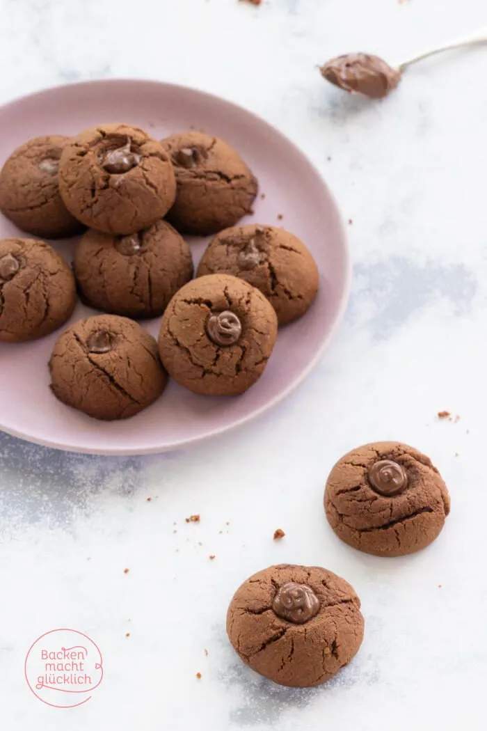 Drei Nutella Kekse, einer davon angeschnitten, zeigen den weichen Schokoladenkern