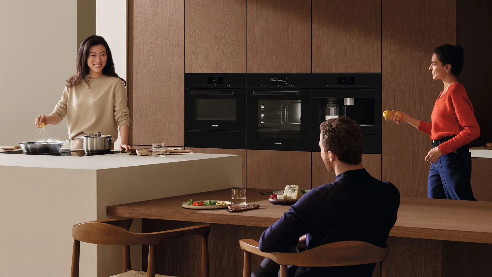 Drei Personen in einer modernen Miele Küche mit vielfältiger Ausstattung