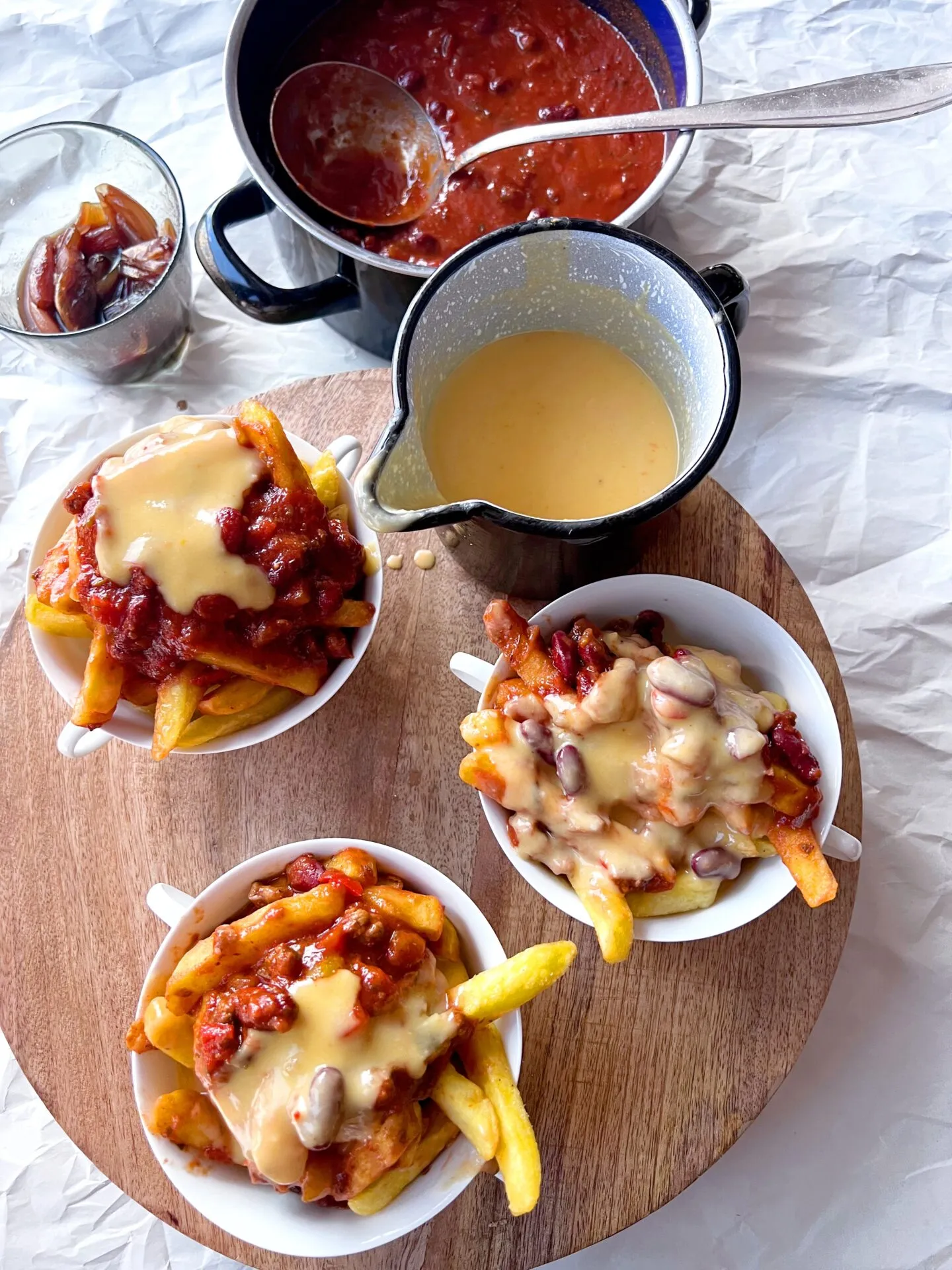Drei Schüsseln mit unterschiedlichen Käsesoßen-Varianten, inklusive Chili Cheese Fries und Käsesuppe