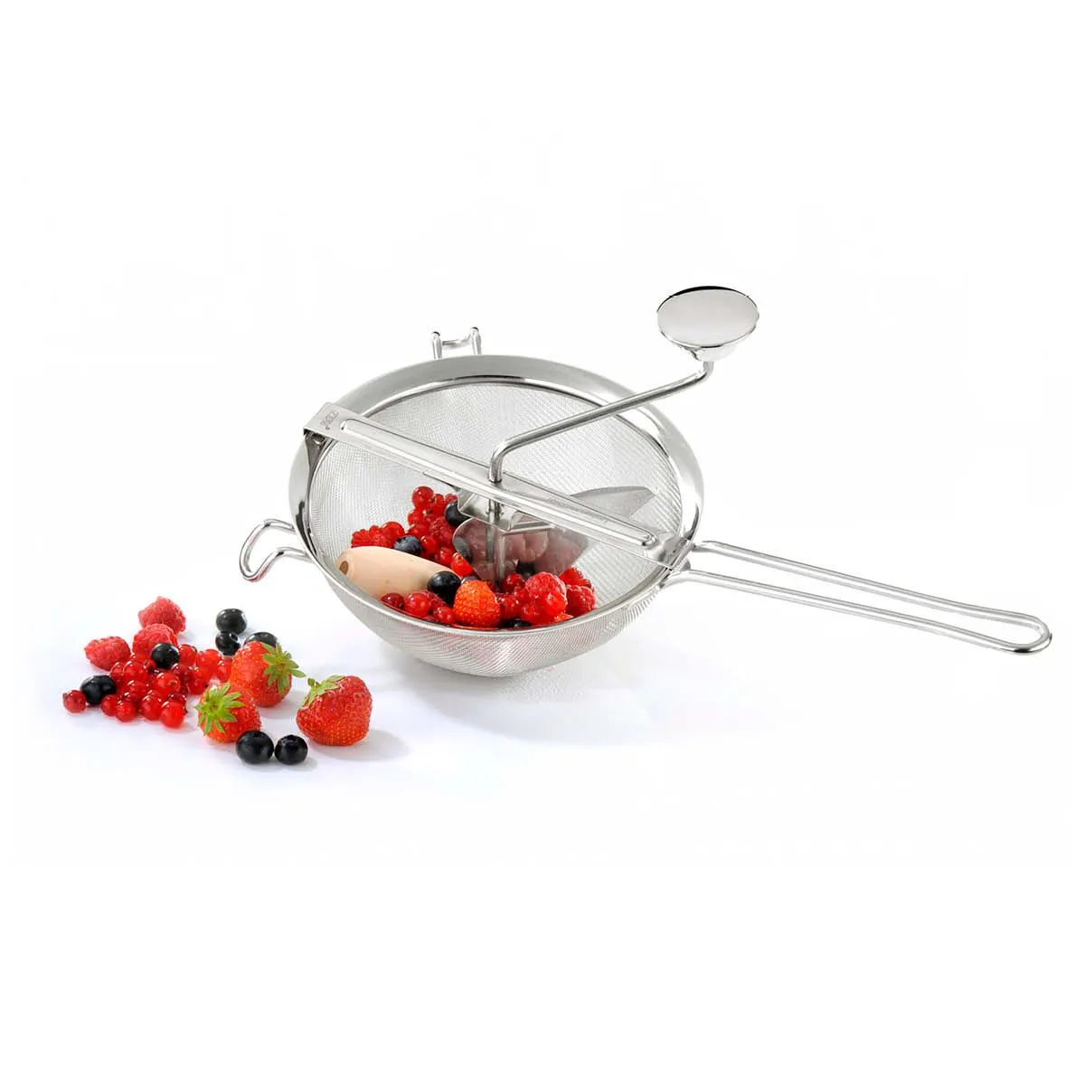 Edelstahl-Passiermühle gefüllt mit Erdbeeren, Johannisbeeren und Heidelbeeren auf weißem Hintergrund