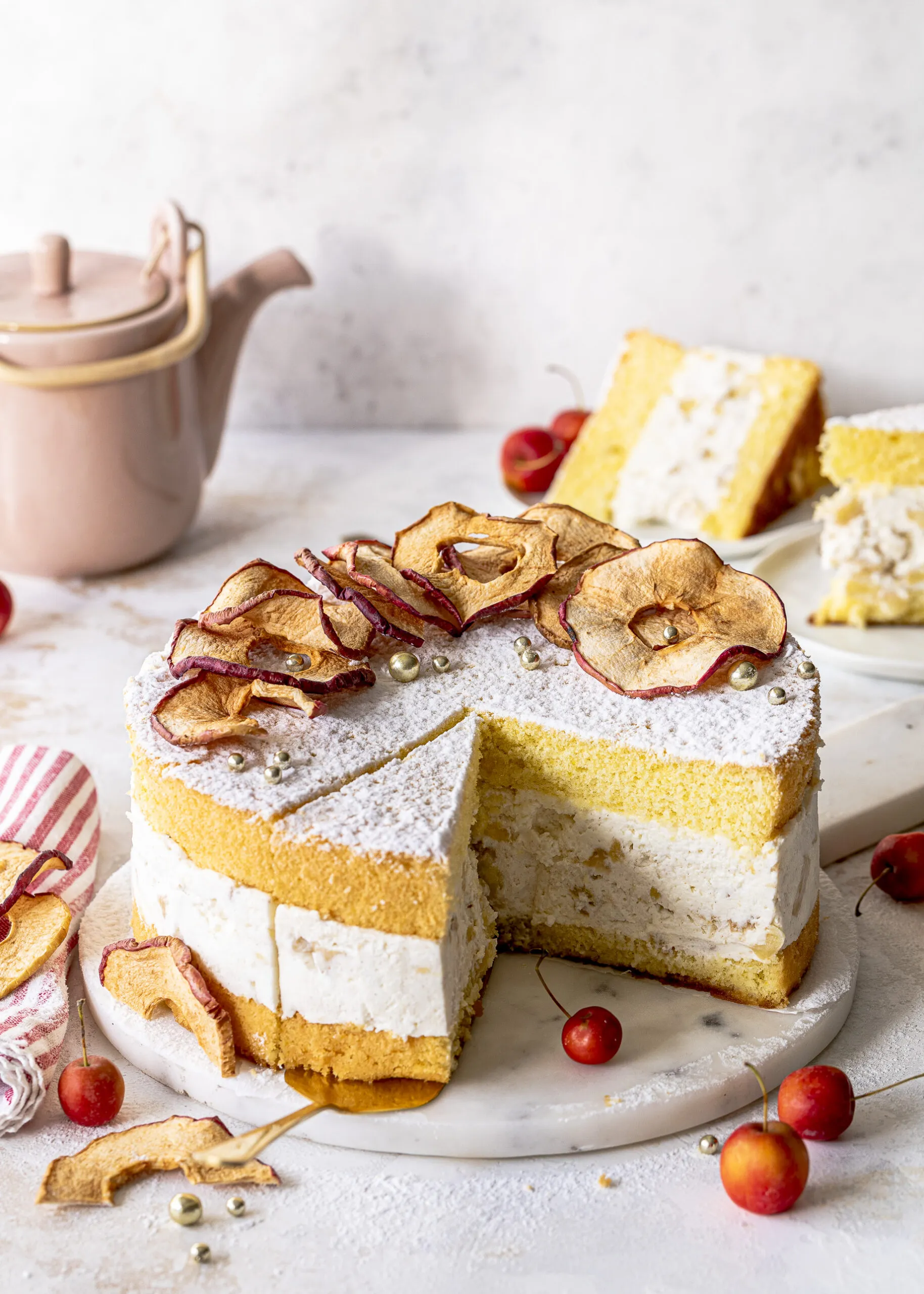 Ein Anschnitt der Bratapfel-Käse-Sahne-Torte, der die cremige Füllung mit Apfelstücken und den Biskuitboden zeigt.