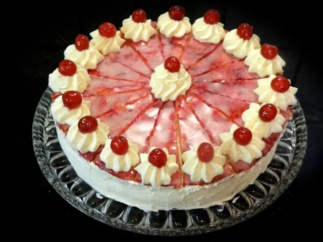 Ein Anschnitt der Holländischen Sahnetorte zeigt die cremigen Schichten und Kirschfüllung