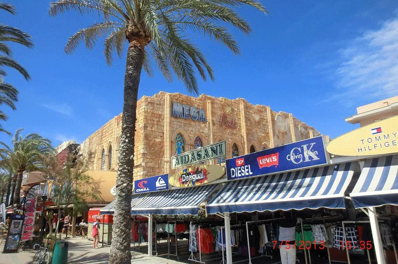 Ein belebter Strand an der Südküste Mallorcas mit vielen Sonnenliegen und Sonnenschirmen