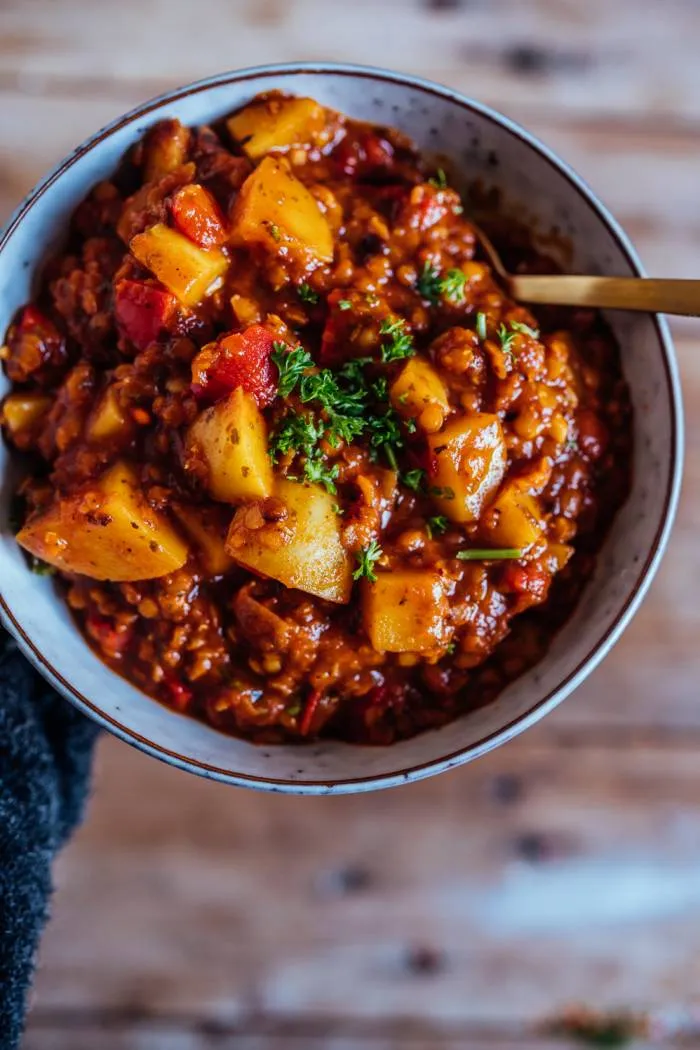 Ein bunter Paprika-Kartoffel-Linsen-Topf in einem großen Topf auf dem Herd, bereit zum Köcheln