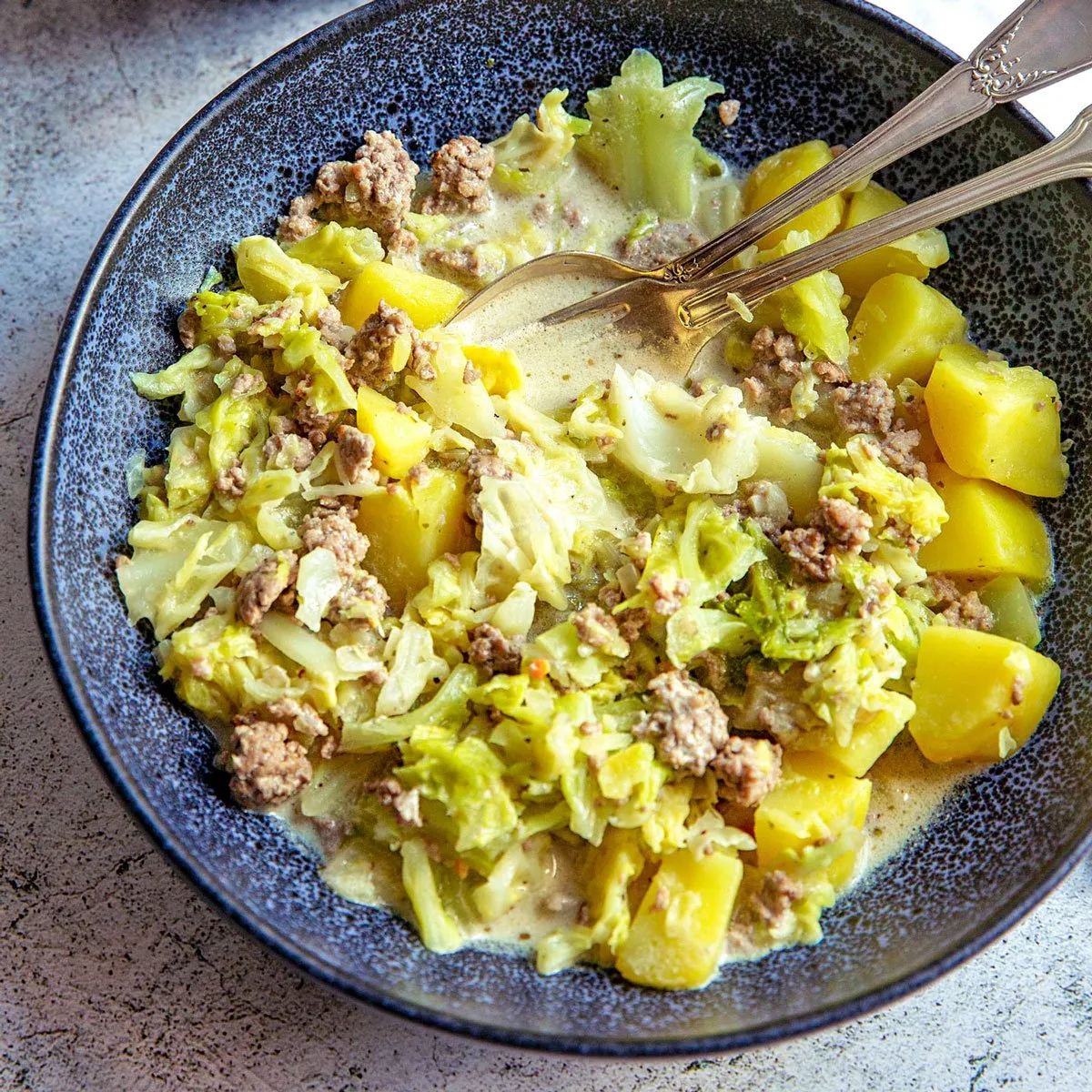 Ein dampfender Wirsing-Eintopf, garniert mit frischer Petersilie, in einem rustikalen Topf auf einem Holztisch
