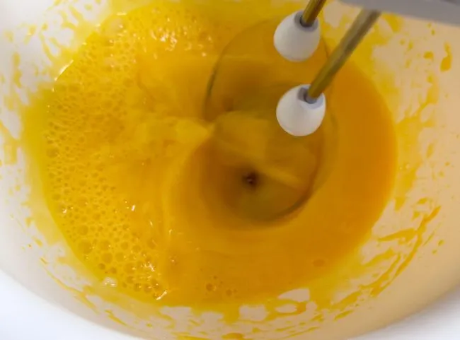 Ein Ei wird mit Rapsöl schaumig gerührt für den Kuchenboden der Geburtstagstorte