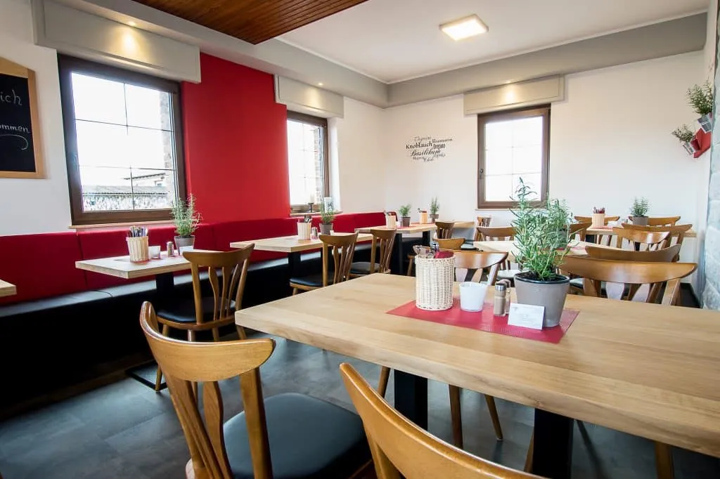 Ein einladender Gastraum mit Tischen, Stühlen und dekorativen Elementen, bereit für Gäste.