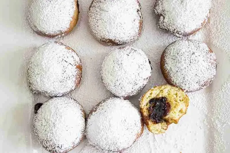 Ein einzelner Berliner Krapfen mit Puderzucker und Marmeladenfüllung
