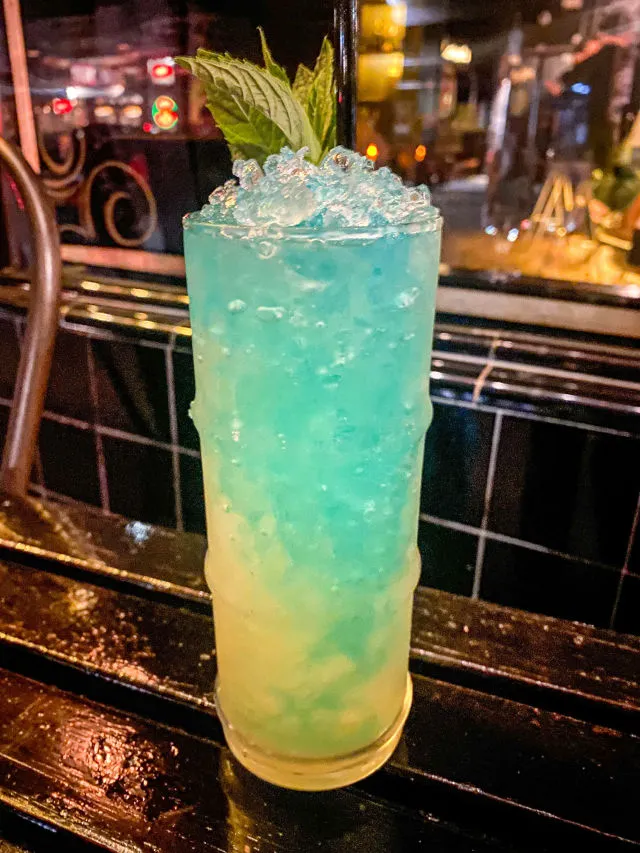 Ein erfrischender, geschichteter Drink mit grünen und blauen Farbtönen in einem hohen Glas, perfekt für sommerliche Anlässe