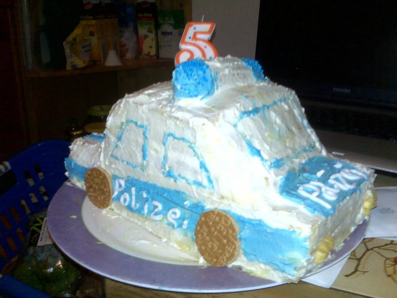 Ein fast fertiger Polizeiautokuchen in Blau, dekoriert mit Sahne und Details