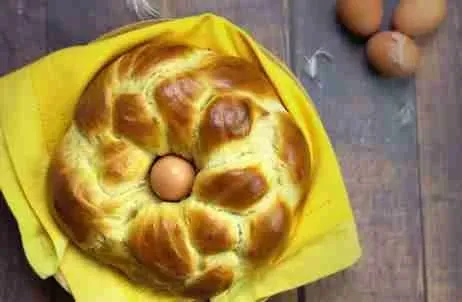 Ein fertig gebackener goldbrauner Osterzopf auf einem rustikalen Holztisch, bereit zum Servieren