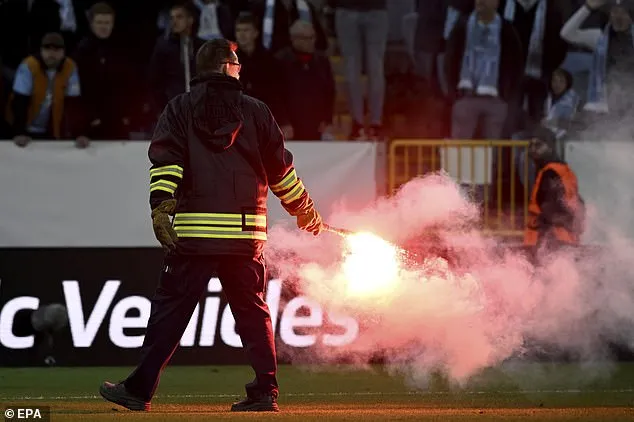 Ein Feuerwehrwehrmann entfernt eine brennende Leuchtrakete vom Spielfeld, nachdem das Europa-League-Spiel unterbrochen wurde.