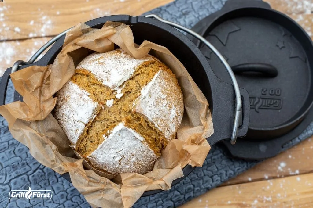 Ein frisch gebackenes, rundes Sodabrot mit Kreuzschnitt im Dutch Oven