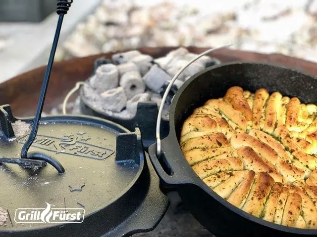 Ein frisches Kräuter Faltenbrot aus dem Dutch Oven auf einem rustikalen Holzbrett