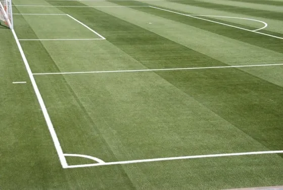Ein Fußballplatz mit grünem Kunstrasen und weißen Markierungen.