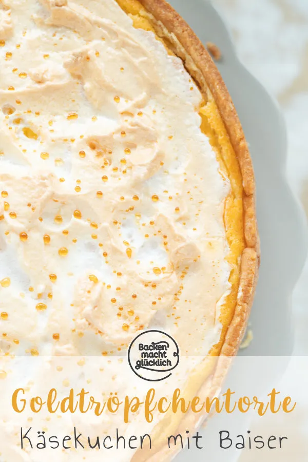 Ein ganzer Goldtröpfchen Käsekuchen auf einem Tortenständer, wunderschön mit seinen goldenen Tröpfchen auf der Baiserhaube präsentiert.