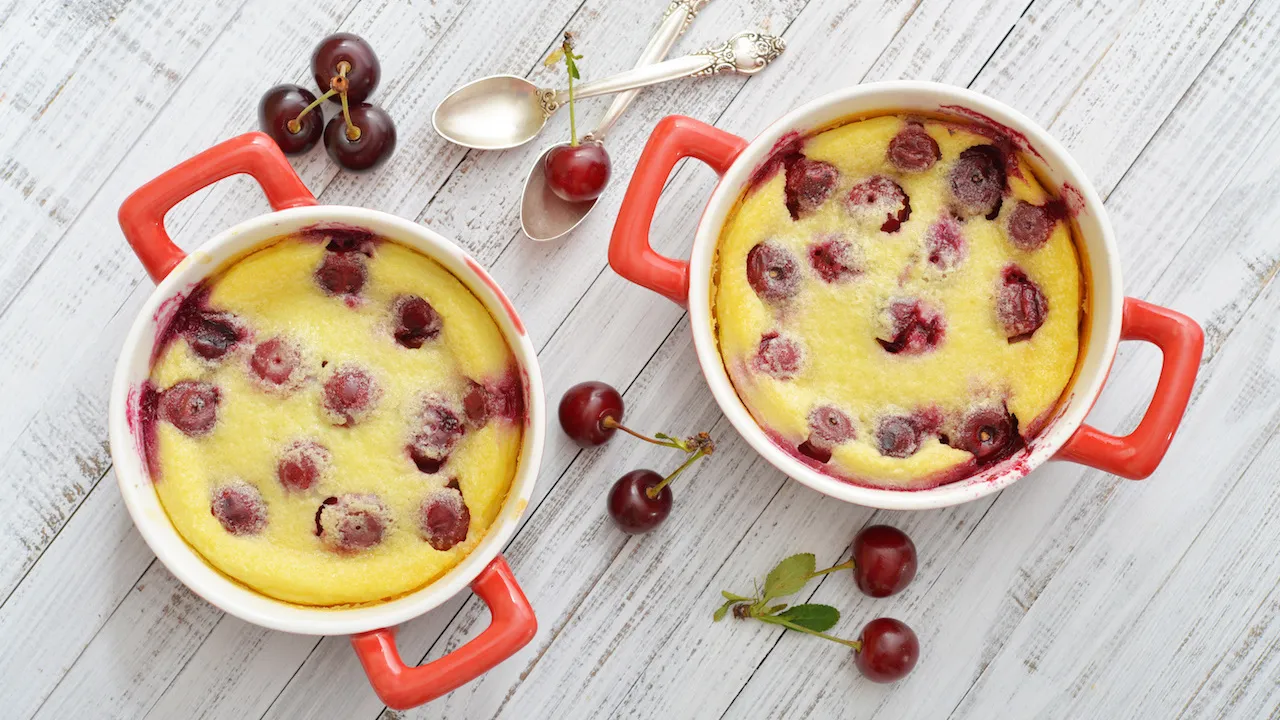 Ein goldbraun gebackener Quarkauflauf mit Kirschen, bestäubt mit Puderzucker