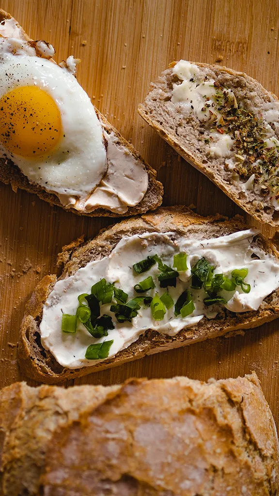 Ein großes, frisch gebackenes Dinkelmischbrot mit einer tiefbraunen, knusprigen Kruste liegt auf einem Holzbrett