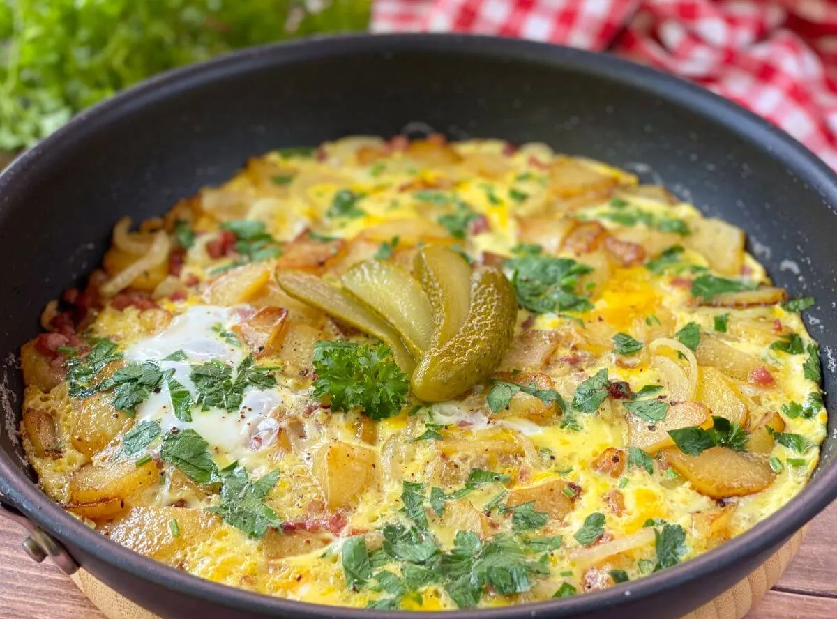 Ein klassisches Bauernfrühstück mit Spiegelei und frischen Kräutern in einer Pfanne