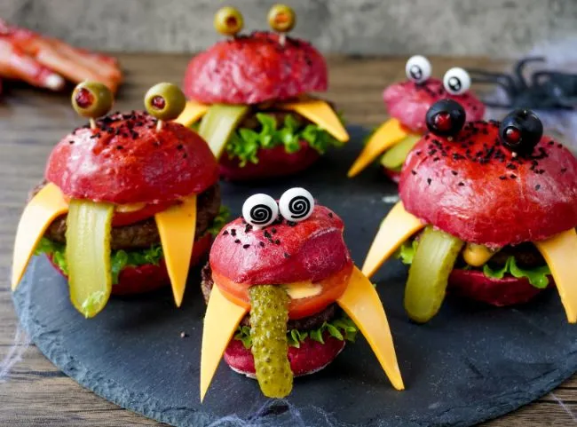 Ein kreativer Halloween Monster Burger mit Olivenaugen und Käse-Zähnen