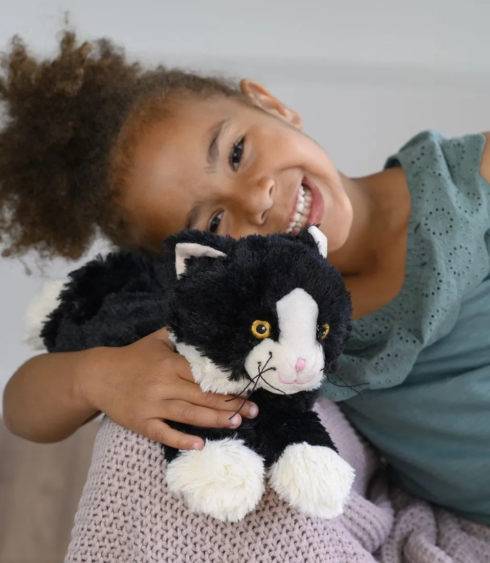 Ein lächelndes Mädchen hält die Warmies® Katze liegend im Arm