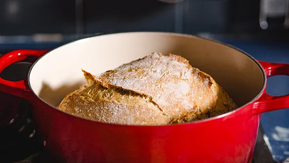 Ein leuchtend roter Gusseisentopf von Le Creuset steht auf einer Küchenoberfläche