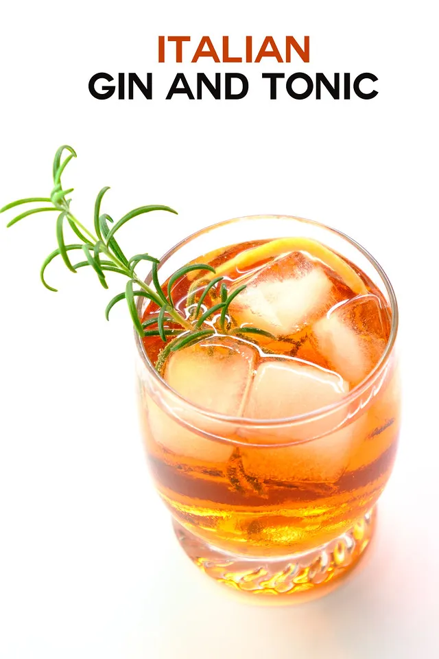 Ein leuchtender, orangefarbener Cocktail, garniert mit einem Rosmarinzweig und einer Orangenspirale