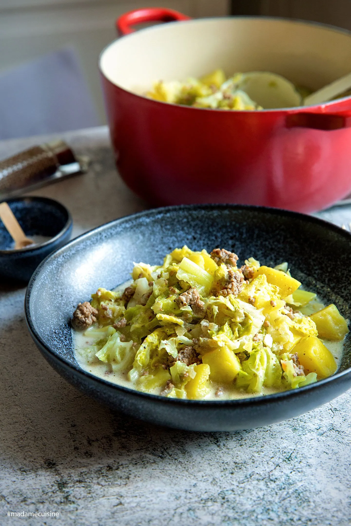 Ein Löffel voll dampfendem Wirsing-Eintopf mit Hackfleisch, Kartoffeln und cremiger Soße