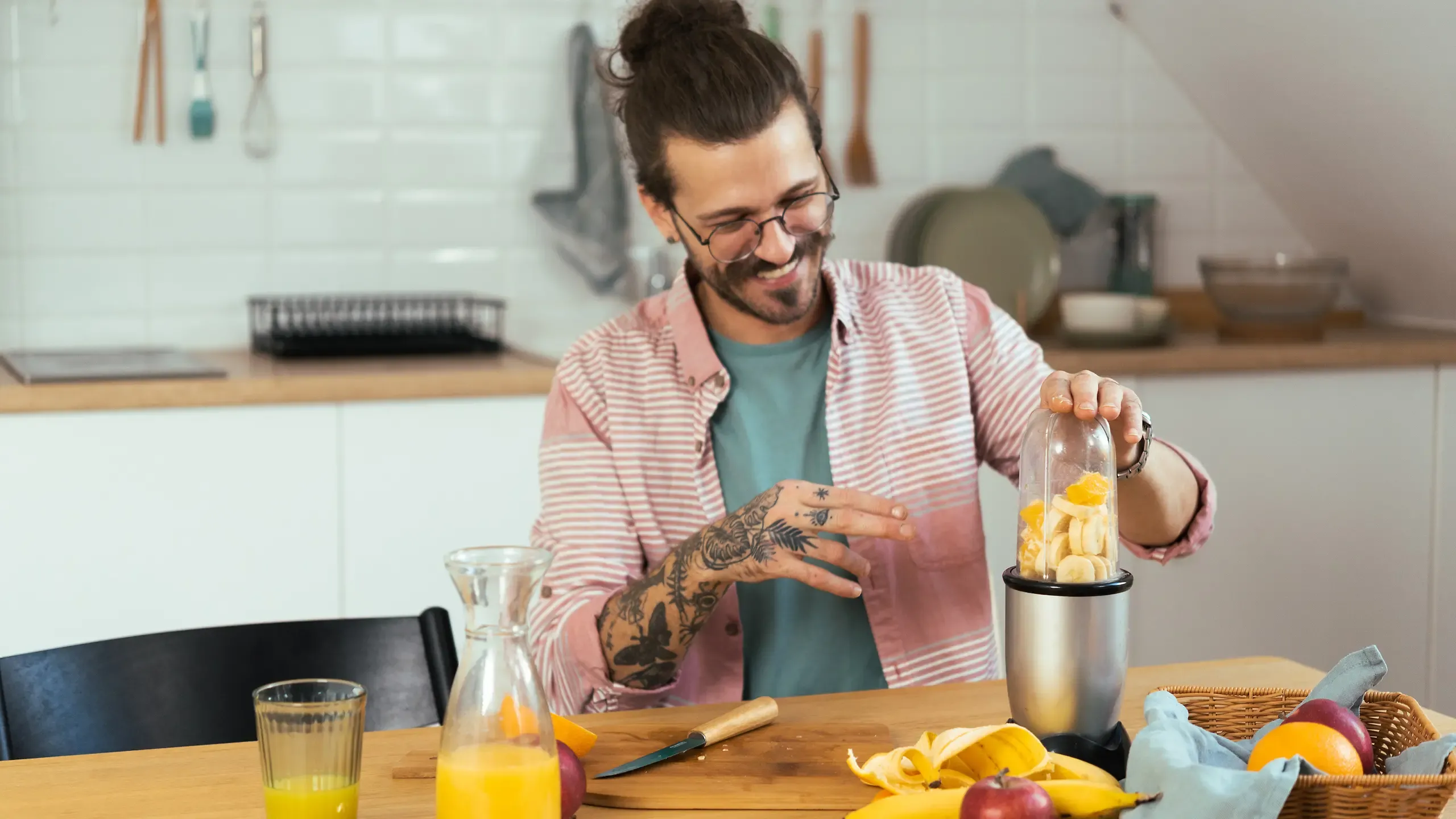 Ein Mann steht in der Küche und bereitet sich einen Saft-Smoothie zu.