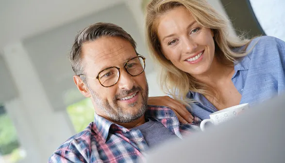 Ein Paar sitzt gemeinsam vor einem Laptop und bespricht Bildungsmöglichkeiten