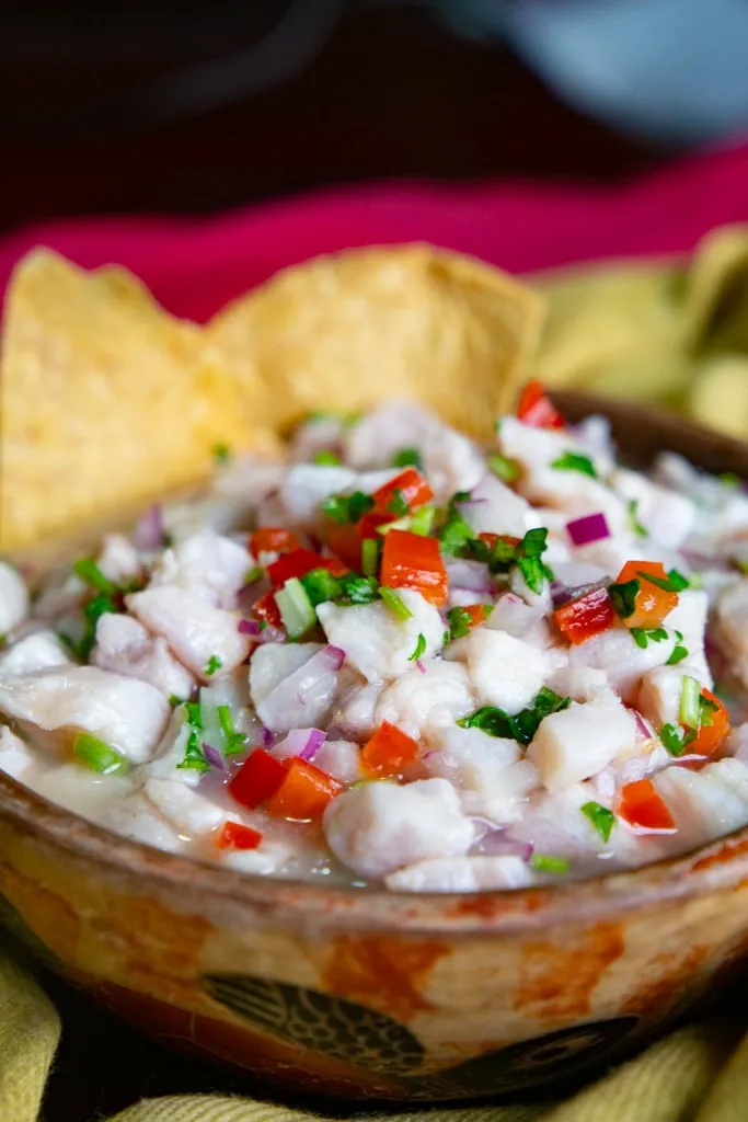 Ein paar Tortilla-Chips tauchen in eine Schüssel mit frischem Fisch-Ceviche ein